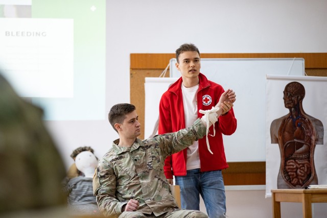 Dr. Georgi Zayov, first aid trainer for the Bulgarian Red Cross, works with a U.S. Army Soldier to demonstrate how to render first aid and control bleeding on a casualty during a combined Bulgarian Red Cross training between U.S. Army Soldiers assigned to the 407th Civil Affairs Battalion and Bulgarian Land Forces soldiers assigned to the Civil-Military Cooperation Company, 78th Support Battalion at Lozen, Bulgaria, May 10, 2022. The coordination between U.S. Army Civil Affairs, Bulgarian Civil-Military Cooperation, and local civilian organizations is crucial in supporting humanitarian assistance and disaster relief in the region, and is necessary to protect and promote humanitarian principles. Bulgaria is a steadfast and gracious host, and the U.S. is honored to continue its long-term cooperation through engagements such as bilateral exchanges to improve partnership interoperability. (U.S. Army photo by Capt. Angelo Mejia, 5th Mobile Public Affairs Detachment)
