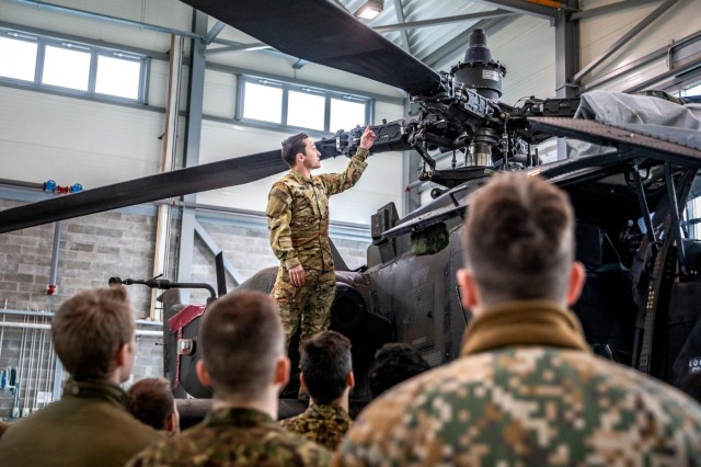 Army 1st. Lt. Mason Conine, an Apache pilot assigned to the Headquarters and Headquarters Company, 1-3rd Attack Battalion, 12th Combat Aviation Brigade, gives a brief on the capabilities of an AH-64D Apache helicopter to NATO joint terminal attack controllers at Lielvarde Air Base in Latvia, March 29, 2022.