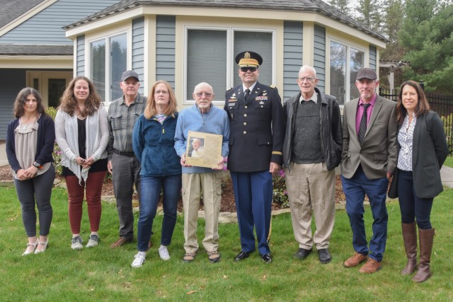 Retired DEVCOM Soldier Center civilian employee Peter Stalker holds his official plaque while posing with his former coworkers from SC&#39;s Aerial Delivery Directorate after a presentation at his home in Massachusetts on April 27 to honor his recent induction into the U.S. Army Quartermaster School Parachute Riggers Hall of Fame.