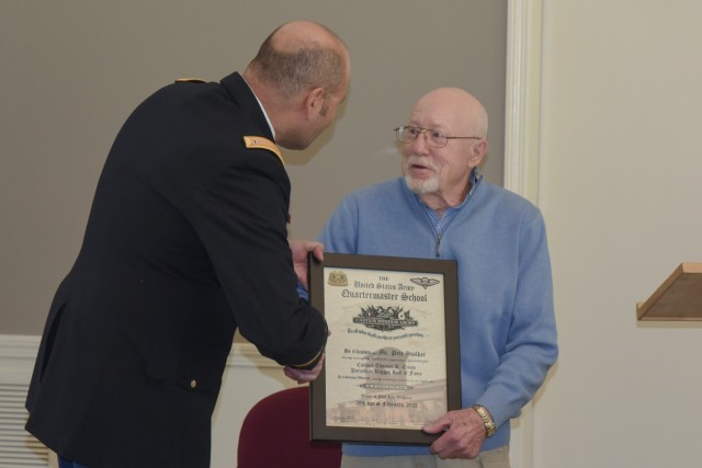 Retired DEVCOM Soldier Center civilian employee Peter Stalker receives an award from Aerial Delivery Directorate Military Liaison Officer CW05 Ismael Ramosbarbosa after being inducted into the U.S. Army Quartermaster School Parachute Riggers Hall of Fame during a presentation held at Stalker&#39;s home on April 27 in Massachusetts.