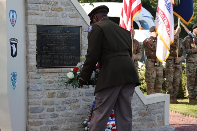 Col. Mark Denton, commander, 207th Military Intelligence Brigade – Theater, seated in the center, places a wreath before a plaque during a ceremony that commemorates and honors the men of Easy Company, 506th Parachute Regiment, 101st Airborne Division who lost their lives when their C-47 aircraft was hit by enemy fire in June of 1944, Sainte Mere Eglise, Normandy, France, June 2.