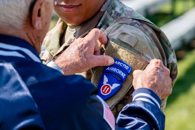 Wayne Porter, a U.S. Army veteran who was assigned to the 11th Airborne Division before its deactivation in 1958, places an 11th Airborne Div. shoulder sleeve insignia on Spc. Jihad Yarber, assigned to the 2nd Brigade, 11th Airborne Division, during the reflagging ceremony of the 11th Airborne Division, June 6, 2022, at Pershing Parade Field, Joint Base Elmendorf-Richardson, Alaska. The activation returns the historic 11th Airborne Division to an active Army role, with a focus on operations in extreme cold weather and mountainous high-altitude environments. The ceremonies at Fort Wainwright and Joint Base Elmendorf-Richardson reflagged the 1st Stryker Brigade Combat Team, 25th Infantry Division and the 4th Infantry Brigade Combat Team (Airborne), 25th Infantry Division, into the 1st and 2nd brigade combat teams, 11th Airborne Division, respectively.