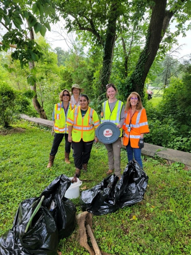 JBM-HH DPW and ANC volunteers with bags full of debris collected along the JBM-HH/ANC property boundary east of Buildings 325 and 330. From left to right: Stacey Rosenquist (ANC), Kelly Wilson (ANC), Agrima Poudel (JBM-HH), Jenny Tolbert (JBM-HH),...