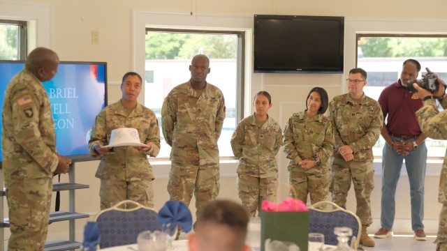 Personnel assigned to the 597th Transportation Brigade Operations Section present Command Sgt. Maj. Lonnie Gabriel a signed hard hat during a farewell luncheon at the Fort Eustis Club at Joint Base Langley-Eustis, Va. June 9.