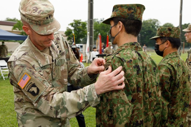 Maj. Gen. JB Vowell, left, commander of U.S. Army Japan, places a new patch on a Japan Ground Self-Defense Force member during a ceremony at Camp Zama, Japan, June 17, 2022. The patch, which combines both the U.S. and Japan flags, symbolizes their enduring bilateral relationship.