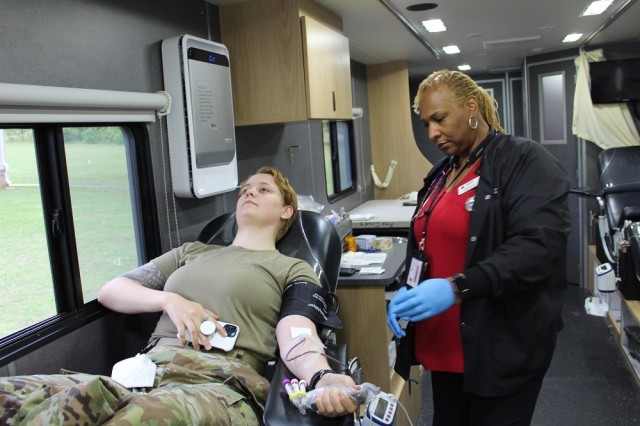 Spc. Sarah Donnell, of Headquarters & Headquarters Company AMCOM, contributes at Friday’s blood drive in the housing area. At right is MaShawn Hampton, charge nurse for the American Red Cross. 