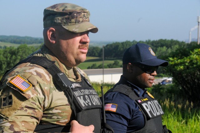 Staff Sgt. Hector Rodriguez (foreground), a Military Working Dog kennel master at Fort Leavenworth, and Lt. Joseph Carroll, Department of the Army Civilian Police, observe teams searching for missing inmates around the U.S. Disciplinary Barracks as part of the 15th Military Police Brigade&#39;s annual missing inmate exercise.