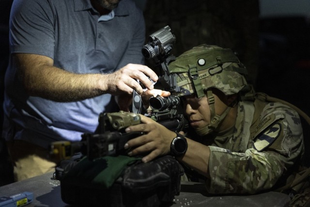 A Soldier tests out a new training device appended to an M4 carbine during a Soldier touchpoint.