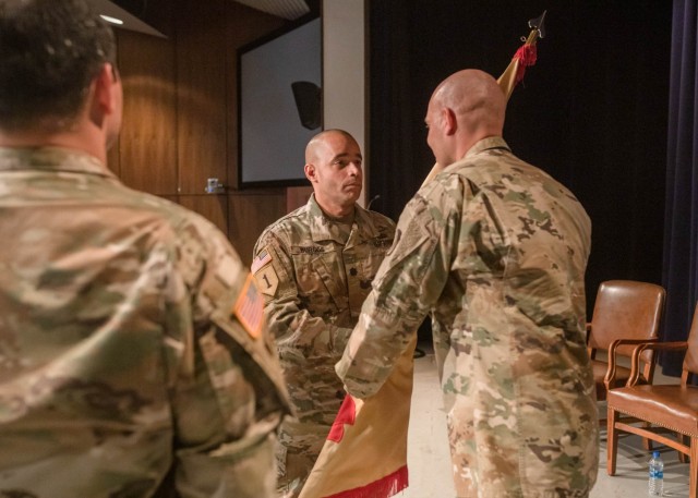 Command Sgt. Terry L. Anderson Jr. (right) passes the Picatinny Arsenal garrison guidon to incoming garrison commander, Lt. Col. Alexander D. Burgos during a change of command ceremony here, June 15.  The outgoing garrison commander, Lt. Col. Adam Woytowich, looks on.
