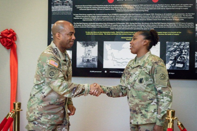 Master Sgt Natasha Carroll, USARCENT Logistics Operations Sergeant receives a coin for excellence from USARCENT Commander, Lt. Gen. Ron Clark, for her dedicated contributions in creating the Red Ball Express display. The Red Ball Express historical display is the latest addition to the many exhibits in Patton Hall. The monograph depicts the heroic actions of the Red Ball Express during WWII.