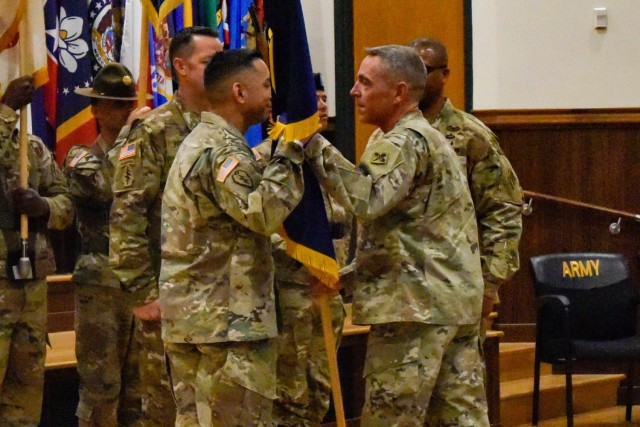 Incoming U.S. Army Chemical, Biological, Radiological and Nuclear School Regimental Command Sgt. Maj. Raymond Quitugua (left) takes the USACBRNS guidon from Col. Sean Crockett, USACBRNS commandant, during a change-of-responsibility ceremony Friday in Lincoln Hall Auditorium. Outgoing Regimental Command Sgt. Maj. Christopher Williams (right, behind Crockett) is retiring after 33 years of service to the U.S. Army. 
