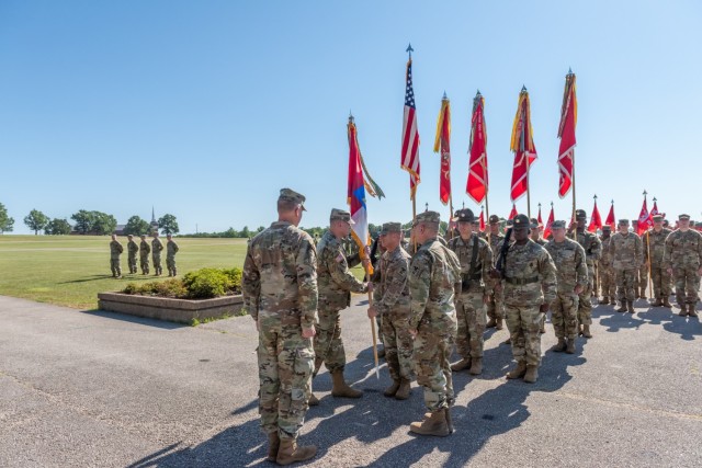 Col. Aaron Bohrer (second from left in the foreground) passes the 1st Engineer Brigade guidon to 1st Engineer Brigade Command Sgt. Maj. Rodney Russell during the 1st Engineer Brigade change-of-command ceremony Wednesday on Gammon Field.