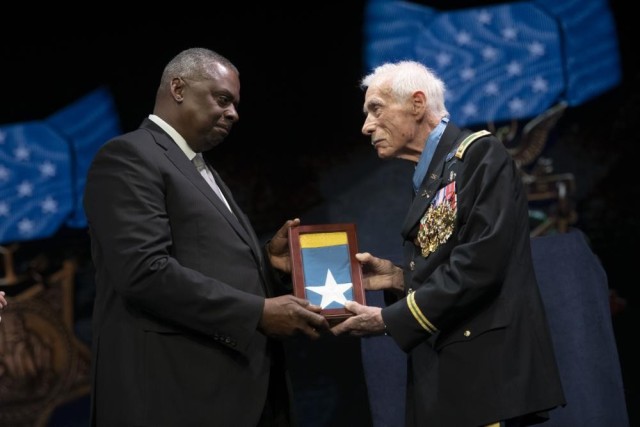 Secretary of Defense Lloyd J. Austin presents the Medal of Honor flag to Army Maj. John Duffy, in a ceremony in which Duffy and five other Medal of Honor recipients were inducted into the Pentagon Hall of Heroes, at Joint Base Myer-Henderson Hall, Va., July 6, 2022. 