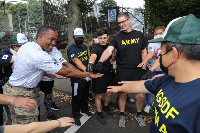 Command Sgt. Maj. Justin E. Turner, left, senior enlisted leader for U.S. Army Garrison Japan, huddles with participants following a beautification project outside the main gate of Camp Zama, Japan, July 8, 2022. More than 20 U.S. Soldiers and Japanese counterparts conducted the cleanup that also aimed to strengthen their partnership.