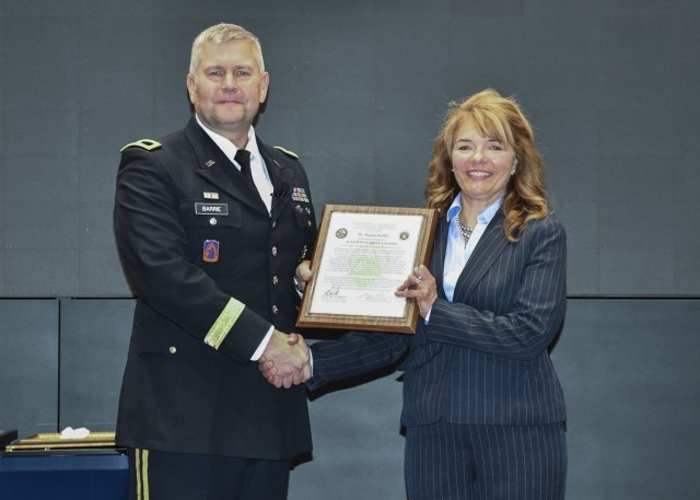 Brig. Gen. Rob Barrie, program executive officer for aviation, presents the Aviation Turbine Engines project office charter to Regina Bublitz during a change of charter ceremony June 23 at Bob Jones Auditorium. Bublitz assumed responsibility from Col. Roger Kuykendall who retired following the ceremony with 28 years of service. 