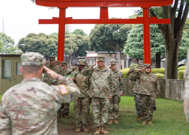 Col. Christopher L. Tomlinson, foreground, commander of U.S. Army Garrison Japan, and military police Soldiers render a salute during a patching ceremony at Camp Zama, Japan, July 12, 2022. 