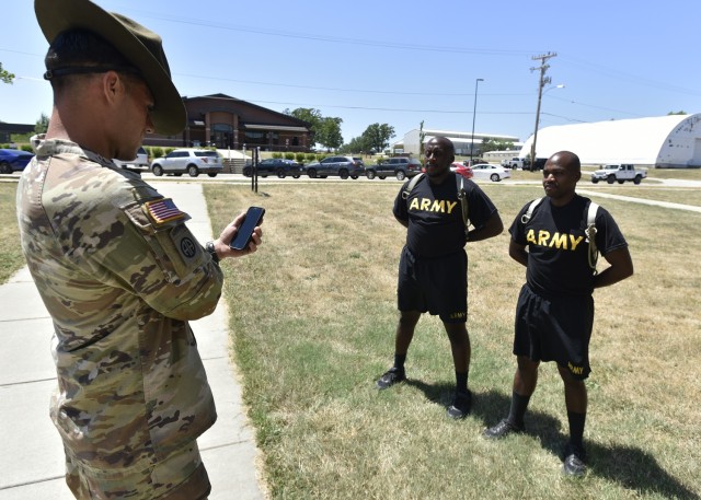 Sgt. 1st Class Brandon Hicks, a senior drill sergeant with Company C, 2nd Battalion, 10th Infantry Regiment, uses his mobile phone to track the core body temperatures of Pfc. Joe Njuki (right) and Pvt. Cedric Shields Monday outside the Charlie Company barracks. To help keep trainees safer during the warmest months here, the Maneuver Support Center of Excellence is facilitating the trial at Initial Entry Training units of a technology called Improving Health Outcomes Through Technology, or IHOTT. Developed at the U.S. Army Research Institute of Environmental Medicine in Natick, Massachusetts, the technology allows cadre to continuously and accurately measure the core body temperatures of every trainee in the unit in real time via body sensors and a downloadable smart-phone application. 