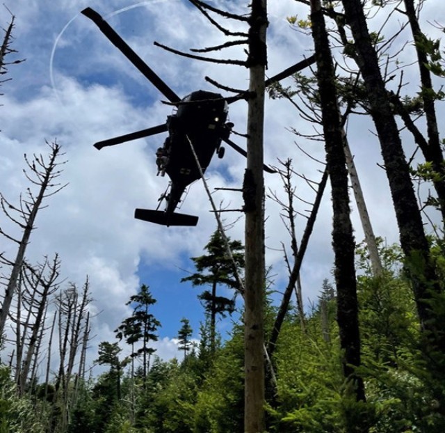 A Tennessee Army National Guard UH-60 Black Hawk helicopter aircrew prepares to hoist a hiker with a life-threatening illness and a Tennessee National Guard flight paramedic into the helicopter on Mount LeConte at the Great Smoky Mountains National Park area July 19, 2022. 