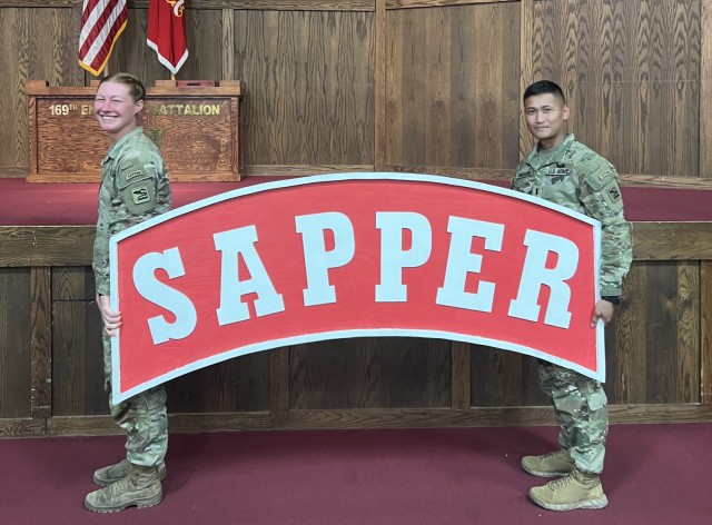 Spc. Lillyanne Clarke and 1st Lt. JP Sumayang, 898th Brigade Engineer Battalion, 81st Stryker Brigade Combat Team, Washington National Guard, hold the Sapper Tab after completing the Sapper Leader Course at Fort Leonard Wood, Missouri, July 1, 2022. (Courtesy Photo)