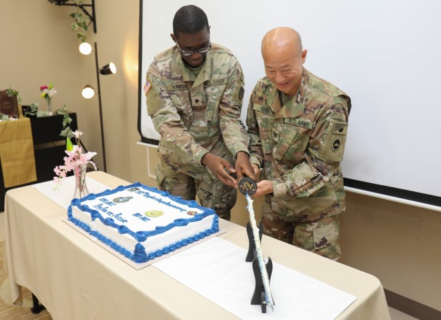 Spc. Matthew Robinson, left, a religious affairs specialist for the U.S. Army Garrison Japan Religious Support Office, and Col. Steve Shin, command chaplain for U.S. Army Japan, place a saber back on its stand after cutting a cake as part of a celebration for the 247th anniversary of the Army Chaplain Corps at Camp Zama, Japan, July 29, 2022.   