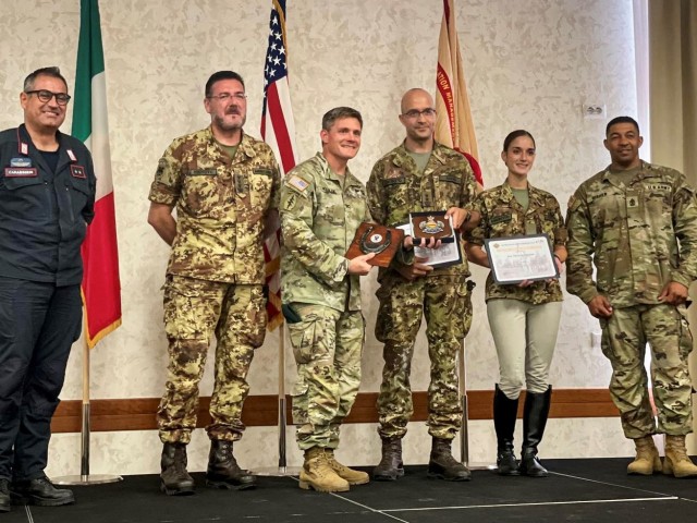 Col. Matthew Gomlak presents awards to Italian soldiers, Tenente Colonel Paolo Anzisi and Artigliere Michela Augusto, for their military horse and artillery display during the garrison’s Independence Day celebration on July 5.