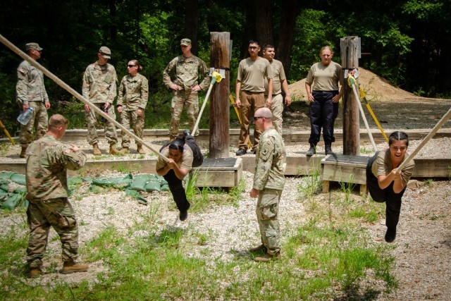 Under the watchful eye of Soldiers from Company E, 701st Military Police Battalion, public safety cadets complete the Single Rope Bridge obstacle of the Physical Endurance Course Wednesday at Training Area 98. The cadets were here for the...