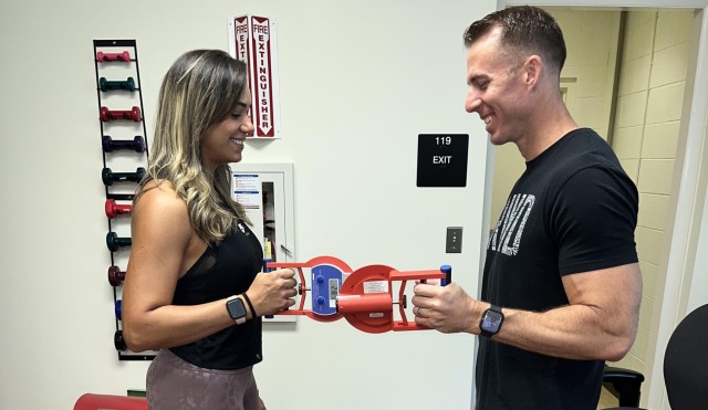 Sgt. 1st Class Justin Woodward, CMF88 Career Management NCO with the 508th Transportation Training Detachment at Fort Lee, Virginia, and his spouse Diellen Couto de Oliveira perform the grip strength test portion of the physical fitness assessment July 26, 2022. The assessment is a screening tool used by the Fort Lee AWC team for the measurement of upper body strength and overall strength.  (U.S. Army photo courtesy Fort Lee Army Wellness Center)