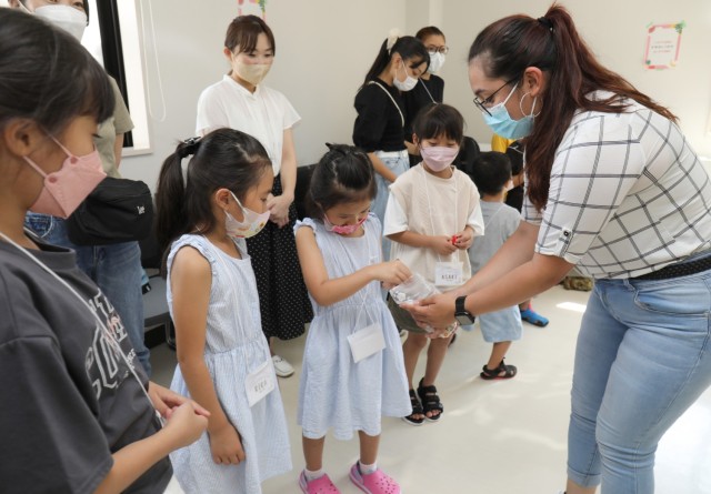 Spc. Lindsey Ruiz, right, a transportation management coordinator with the 623rd Movement Control Team, hands out candies to Japanese students during an outreach event at the Sagamihara Shiritsu Oyama Community Center, Japan, Aug. 10, 2022. Ruiz...