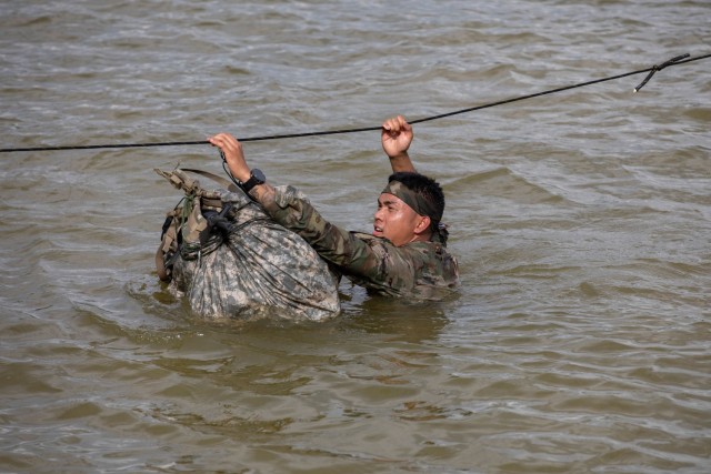 Army Sgt. Fred M. Lino Jr., a small arms/artillery repairer assigned to the Hawaii National Guard&#39;s Echo Troop, Forward Support Company, 29th Brigade Support Battalion, carries his ruck through a water crossing event at the Army National Guard Best Warrior Competition in Milan, Tenn., July 26, 2022.