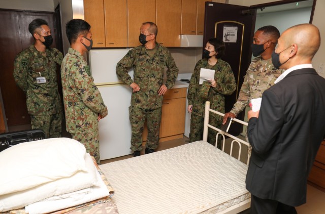 Warrant Officer Masanobu Murawaki, center, the sergeant major of the Japan Ground Self-Defense Force, tours a barracks room where JGSDF members stayed while they participated in the Cooperative Work Program at Camp Zama, Japan.  Murawaki took part in an installation tour Aug.  16, 2022, to better understand how American and Japanese partners interact in the program. 