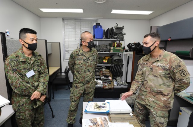 Master Sgt. Juan Polanco, right, noncommissioned officer in charge of preventive medicine at Public Health Command-Pacific, briefs Warrant Officer Masanobu Murawaki, center, the sergeant major of the Japan Ground Self-Defense Force, during his visit to Camp Zama, Japan, Aug. 16, 2022. Murawaki took part in an installation tour to better understand how American and Japanese partners interact in the Cooperative Work Program. 