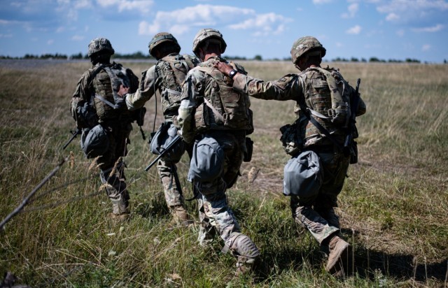 U.S. Army Soldiers assigned to the 66th Military Intelligence Brigade make their way towards a UH-60 Blackhawk during a medical lane at the U.S. Army Europe and Africa Best Squad Competition in Grafenwoehr, Germany, on August 10, 2022.