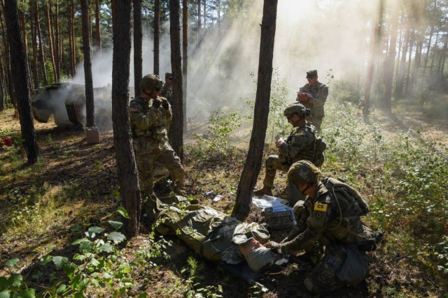 U.S. Soldiers assigned to V Corps team provide first aid to a manikin during the U.S. Army Europe and Africa Best Squad Competition at Grafenwoehr Training Area, Germany, Aug. 9, 2022.