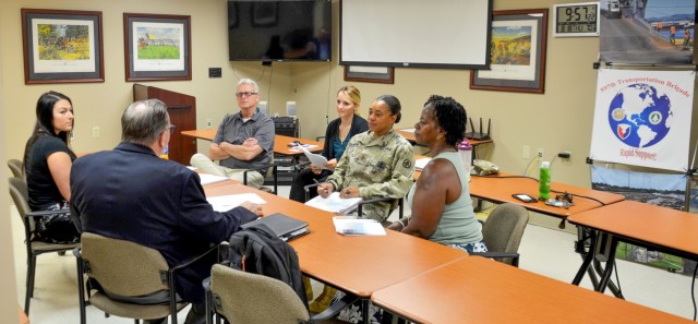 Bil Letchford, Katie Keller, Sgt. 1st Class Terri Francois, and Faye Banks discuss the traffic management mission of the Ocean Cargo Clearance Authority Booking Team with office with Dave DeBoer and Kristyn Valentine of Liberty Global Logistics Aug. 18.