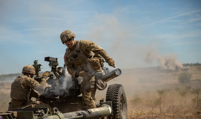 Pfc. Justin Schmitt (right), assigned to 1st Battalion, 134th Field Artillery Regiment, tosses the casing of a 105 mm artillery round during a direct fire exercise as part of Operation Northern Strike at Camp Grayling, Mich., Aug. 12, 2022....