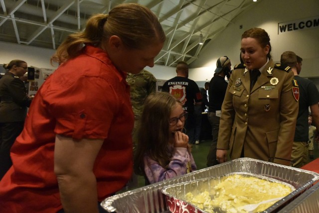 Five-year-old Regan Batey, daughter of 35th Engineer Battalion Commander Lt. Col. Crystal Batey, tries a Romanian dessert at the Know Your World event Friday at Nutter Field House. 