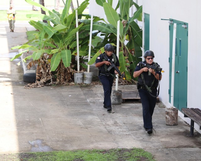 Fort Buchanan Police Officers arrived at the AHS warehouse area while the installation remained in lockdown/shelter in place. An Observer and Controller (L) follows behind the Police evaluating the exercise.