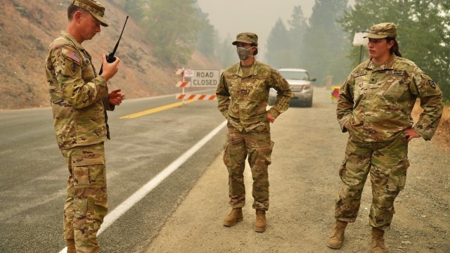 Deep in the Rum Creek Fire Complex area, Sgt. Jeremy Hensler conducts a radio check for teammates Staff Sgt. Casey Reed and Spc. Britney Rivera at Road Closure Point #1 near Merlin, Ore. Sept. 2, 2022. Oregon National Guard members support the Rum Creek fire fighting efforts with traffic control, road closure points, and medical air evacuation helicopter assets.