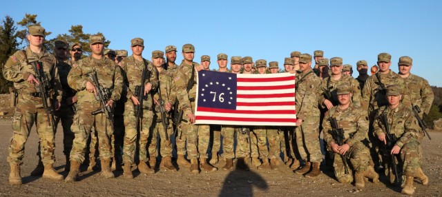 HOHENFELS, Germany - U.S. Army Spc. Jacob Holley (left holding flag), an infantryman assigned to Charlie Company, 1st Battalion, 149th Infantry Regiment, and others from 1st Platoon pose for a photo with a flag belonging to Holley’s grandfather in Hohenfels, Germany February 23, 2022. 1st Battalion, 149th Infantry Regiment is currently serving in Kosovo as part of the approximately 3,700 troops serving with the NATO-led Kosovo Force mission. 