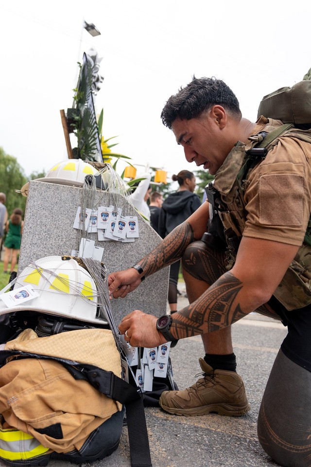 A Soldier hangs a tags bearing the name of a firefighter killed by the 9/11 terrorist attacks on a memorial at Camp Walker, Republic of Korea, September 12, 2022. The tags were placed at the memorial following a 2-mile run. Runners wore the tags of individual firefighters lost to honor their sacrifice.