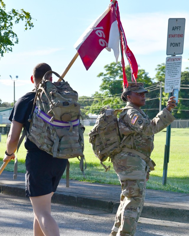 Fort Buchanan Garrison Commander Col. Tomika M. Seaberry stands next to the 166th RSG Brigade Guidon Bearer as she photographed Soldiers during the 9/11 ruck march on the installation’s Perimeter Road.