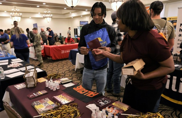 A representative from one of the numerous education institutions set up at the Fort Knox Saber & Quill Sep. 15, 2022 hands a business card to an attendee of the Career & Education Fair.