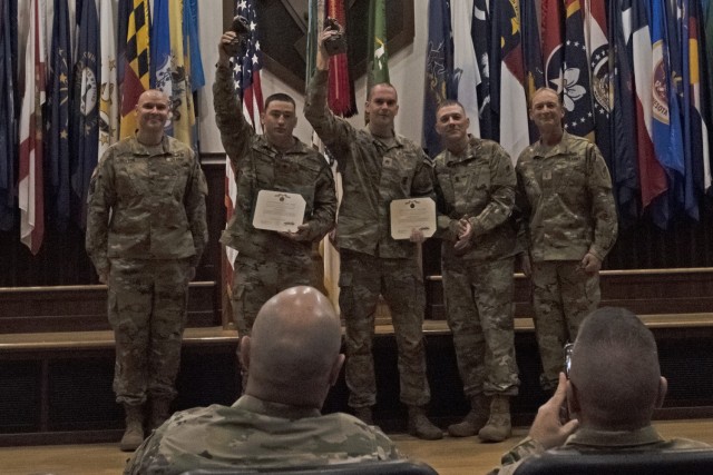 Staff Sgt. Adam Walter (center) and Spc. Mikel Dillon (second from left), from the 91st MP Battalion, at Fort Drum, New York, hold up their trophies Tuesday morning in Lincoln Hall Auditorium after being named the overall team category winners of the 2022 MP Competitive Challenge. 