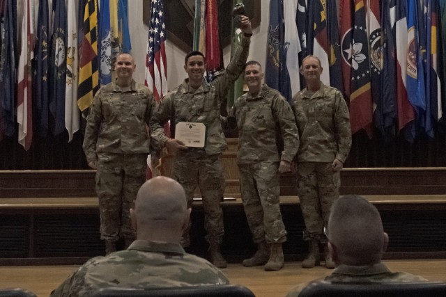 2nd Lt. Carlos Paiz, a platoon leader from Company E, 701st Military Police Battalion (second from left), holds up his trophy Tuesday morning in Lincoln Hall Auditorium after being named the overall officer category winner of the 2022 MP Competitive Challenge. 