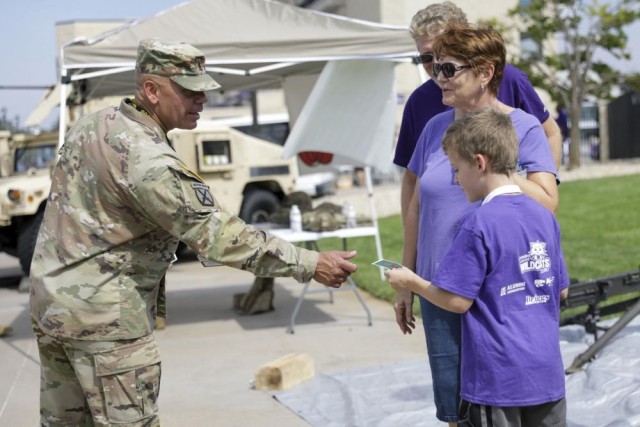 1st Infantry Division Command Sergeant Major-Riley, U.S. Army Command Sgt. Maj. Albert Serrano, hands out stickers to children in front of static displays during Kansas State University’s Fort Riley Day, September 17, 2022. KSU holds their Fort Riley Appreciation Day annually, where they honor military service members both at home and overseas. (U.S. Army photo by Sgt. Dahnyce Baucom)