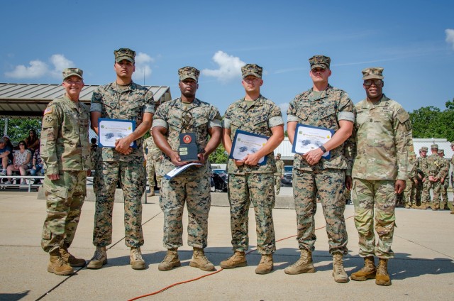 U.S. Army Chief of Transportation and Commandant of the U.S. Army Transportation School, Col. Beth Behn (left), and Transportation Corps Regimental Command Sgt. Maj. Randy Brown (right), stand with (from left) Cpl. Eduardo Tapia, Staff Sgt. Raphael Johnson, Cpl. Clayton Ainscough and Staff Sgt. Dustin Backe, from the Fort Leonard Wood Marine Corps Detachment Friday at Training Area 228, after the Marine Corps team won the 2022 Joint Service Truck Rodeo. 