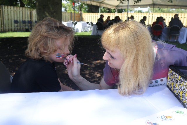 Gold Star family member Jerry “JJ” Heath Jr., 7, sits still while volunteer Elizabeth Cottrell paints an American flag on his face during a picnic held for Gold Star family members at Quarters One Sept. 10, 2022. 