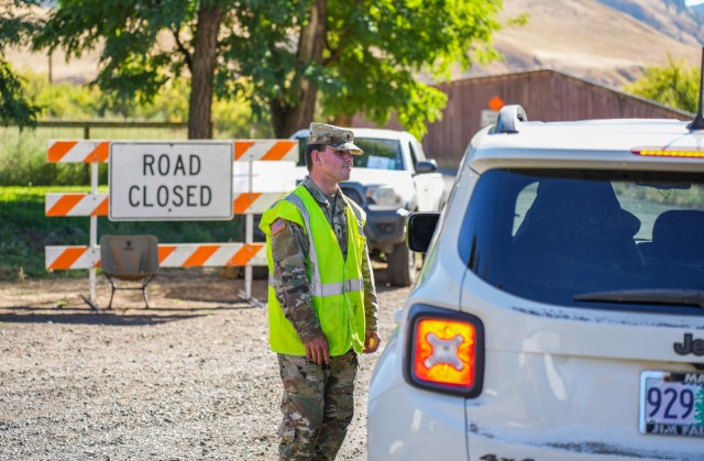 Oregon Army National Guard Spc. Zack Baker, a Double Creek Fire volunteer, talks with residents at a road closure point in Imnaha, Ore., Sept. 23, 2022. Baker and fellow Guard members are staffing road closure points around the perimeter of the Double Creek Megafire in the Wallowa Whitman National Forest area. (Maj. Wayne Clyne)
