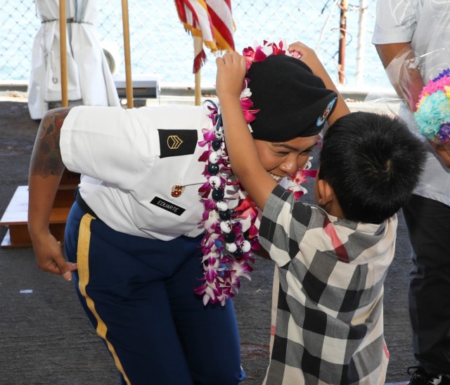 SSG Eduarte, of 8th Theater Sustainment Command, receives a lei from her son after her promotion ceremony.
