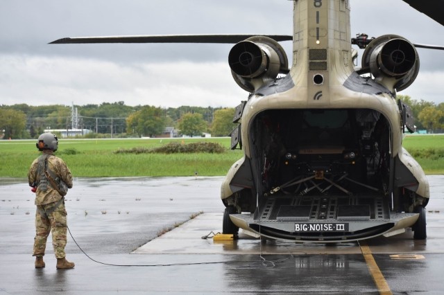 A New York Army National Guard Soldier assigned to B Company of the 3rd Battalion, 126th Aviation Regiment watches as a CH-47F prepares to start engines on Wednesday, Sept. 28, 2022 at Frederick Douglas Greater Rochester International Airport, en route to Florida to assist in hurricane response missions. At the direction of Governor Kathy Hochul, 11 Soldiers and two CH-47F Chinook heavy lift helicopters were dispatched to Florida.